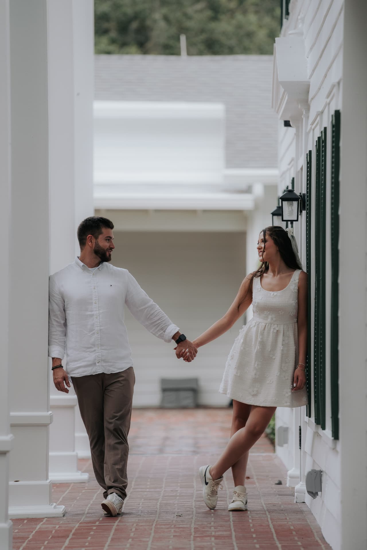 Jenni e Pedro de mãos dadas no corredor branco